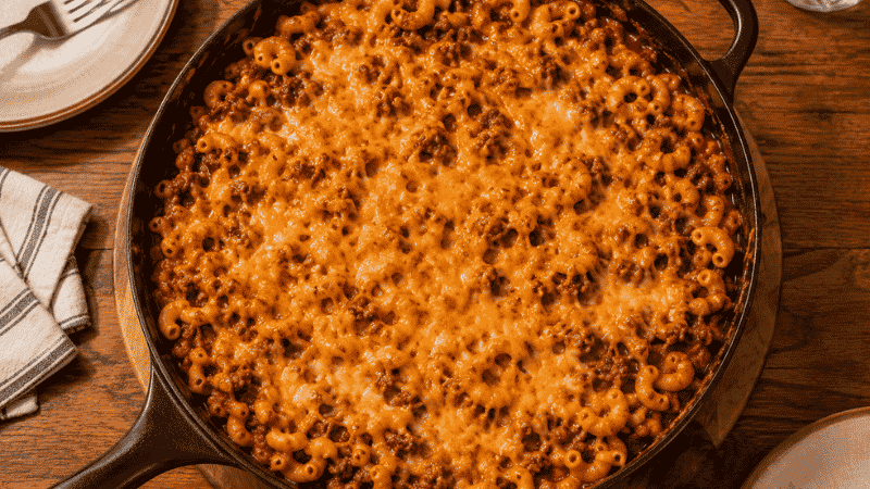 Skillet of chili mac with melted cheddar cheese — a cheap one-pot family meal under $8 total that picky eaters consistently clean their plates
