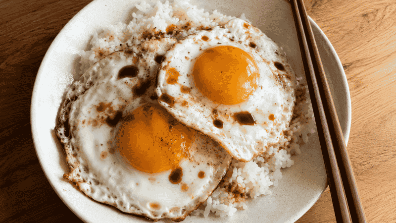 Two fried eggs over white rice with soy sauce — the 10-minute backup cheap family meal for picky eaters that costs under 50 cents per serving