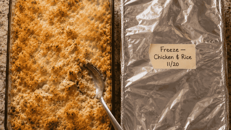 Two chicken and rice casserole dishes — one fresh from the oven, one covered and labeled for freezing — the double batch strategy for cheap large family meals