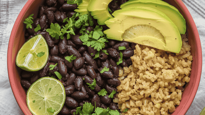 A healthy black bean power bowl with avocado, brown rice, and lime wedges, showing a quick meal made with canned beans.